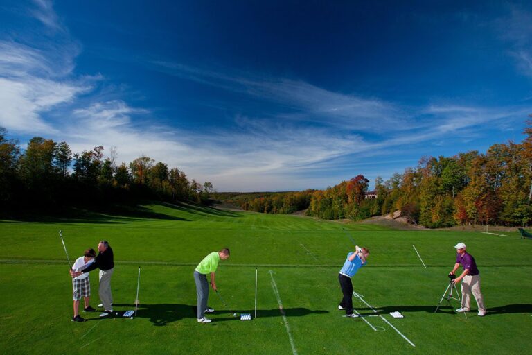 Two PGA Professional Instructors work with three golfers at the Treetops Resort driving range.