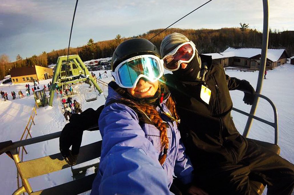 Two smiling people on a chair lift in Gaylord, MI at Treetops Resort.