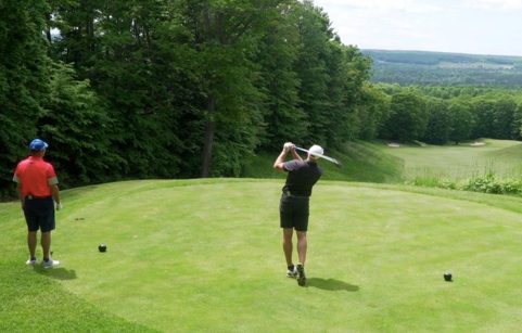 Male golfer teeing off with friend looking on | golf exercises